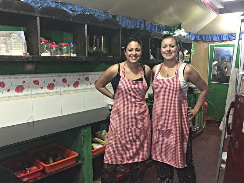 Two women in aprons during a cooking class in Kerala, India
