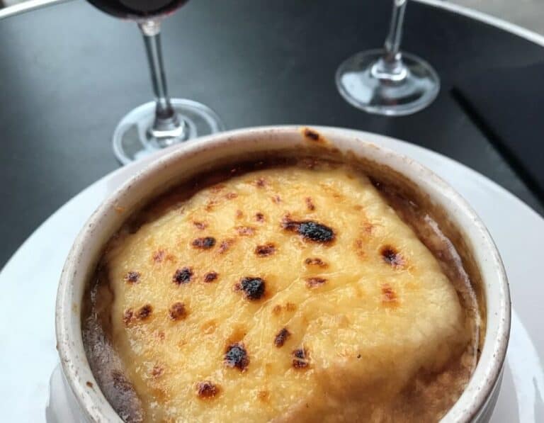 A bowl of French Onion soup as served in Paris with a glass of red wine for the winter