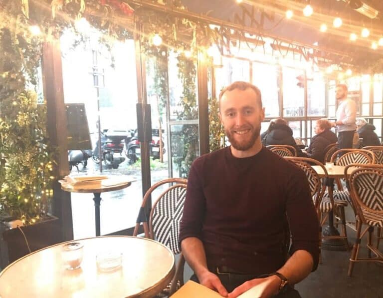 Jack enjoying the Cafe Culture in Paris as he sits on a chair 