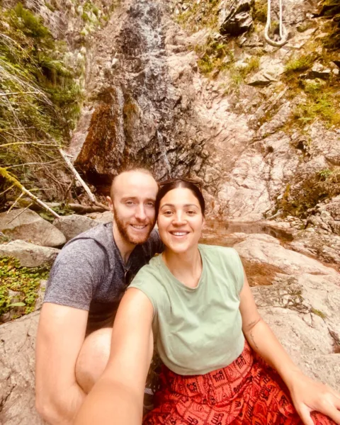 Jack and Abi in Kruth, Alsace with small waterfall behind them