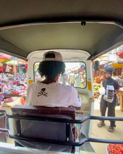 Man inside a tuk tuk driving through a market in Sierra Leone