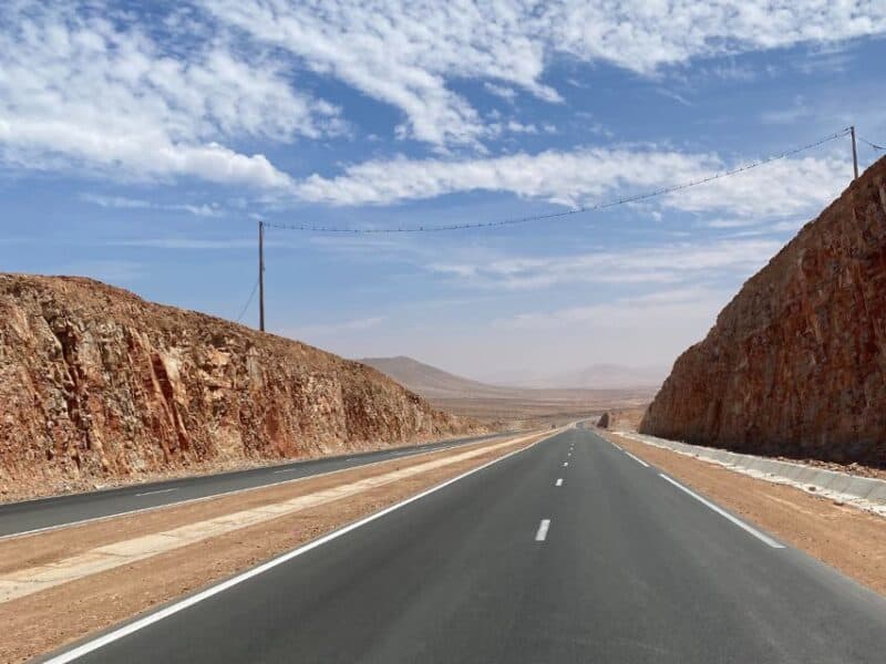 A long road in Morocco with cliffs either side.