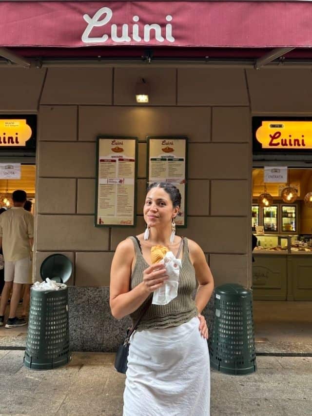 Abi posing with a panzerotti in here hand standing in front of Luini's in Milan.