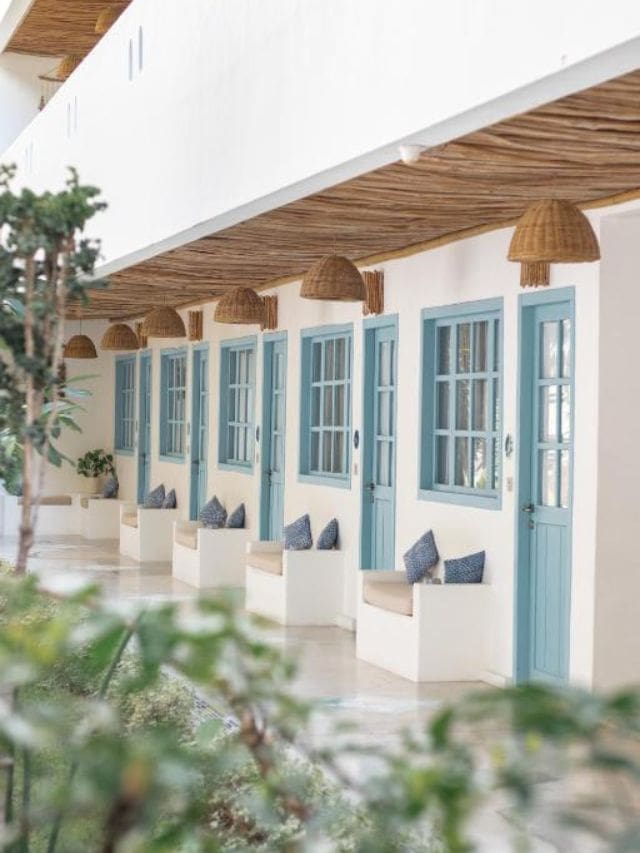 Bright budget hotel corridor in Labuan Bajo with blue doors and woven lampshades