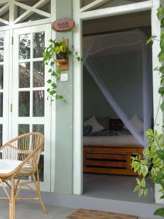 Deluxe double room entrance at Ella Ceylonka with veranda chair and mosquito net bed.