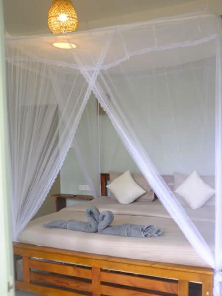 Double bed with mosquito net inside Ella Ceylonka guesthouse in Ella.