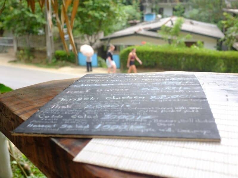 Café menu at Ella Ceylonka with the road and greenery in the background.