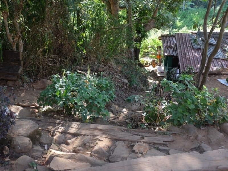 Rocky steps descending towards a house and stream on the self-guided route to Ella Rock.