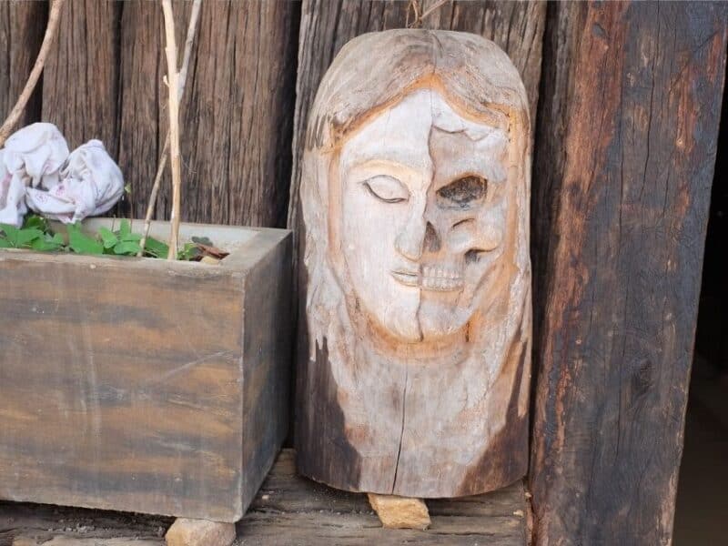 Carved wooden face showing half human and half skull outside the Forest Monastery near Ella.