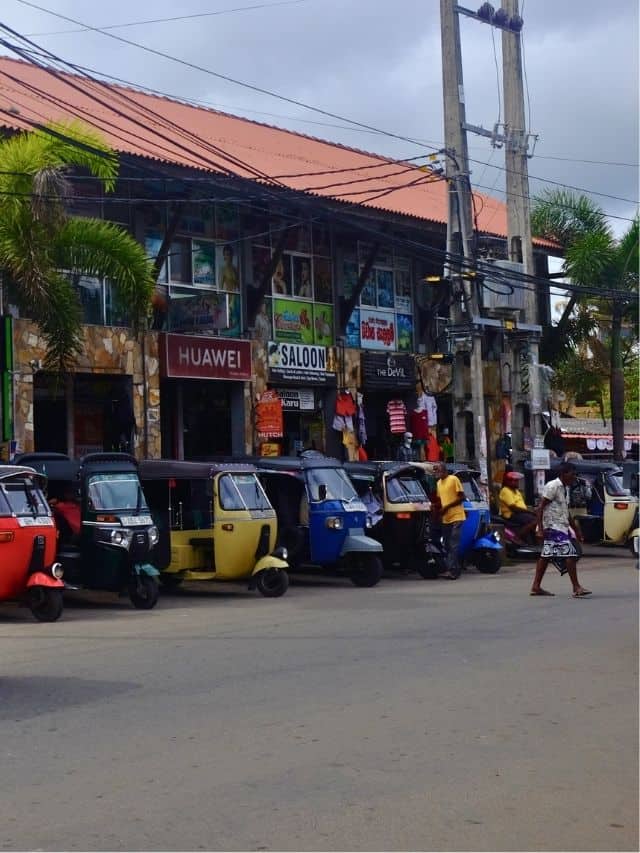 Tuk-tuks lined up on a busy street in Dickwella, Sri Lanka