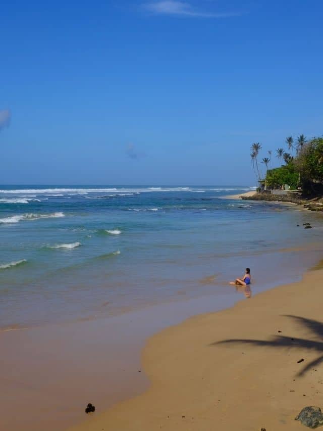 Women sitting in the sand on a beach in Ahangama, Sri Lanka.