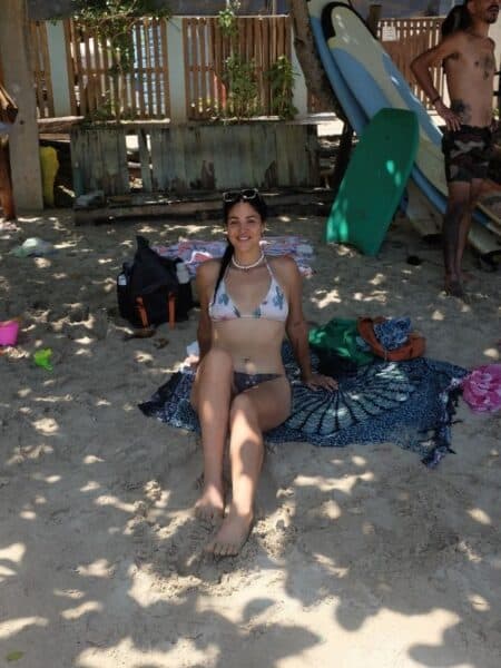 Woman sitting on a beach towel in the shade at Hiriketiya Beach