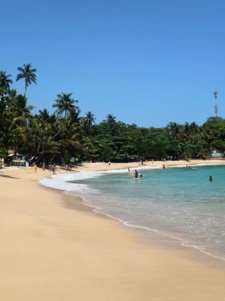 People swimming in the shallow water at Hiriketiya Bay