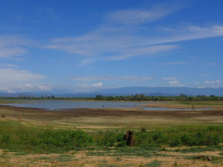 Ella to Udawalawe Safari wetland landscape with open water, dry grassland and distant mountains in Sri Lanka