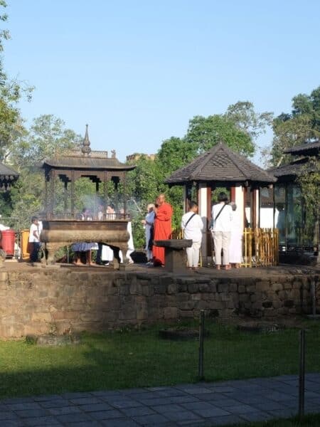 Monks and visitors near a shrine at the Temple of the Tooth in Kandy, Sri Lanka