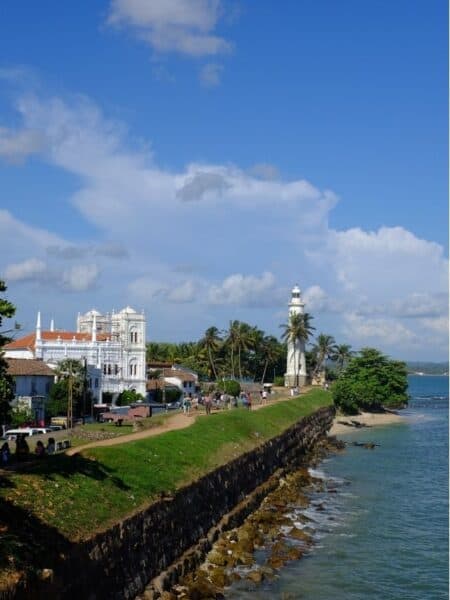 Galle Fort lighthouse and ramparts overlooking the ocean on a sunny day in Sri Lanka.