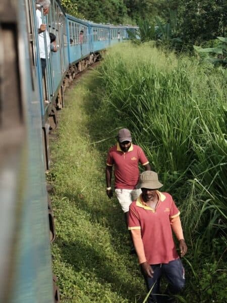 Railway workers beside the blue train on the scenic Kandy to Ella route in Sri Lanka.
