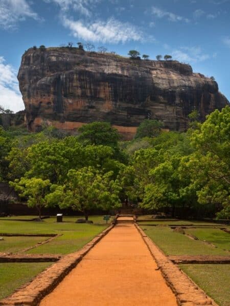 Sigiriya Lion Rock rising above green gardens and forest in Sri Lanka.