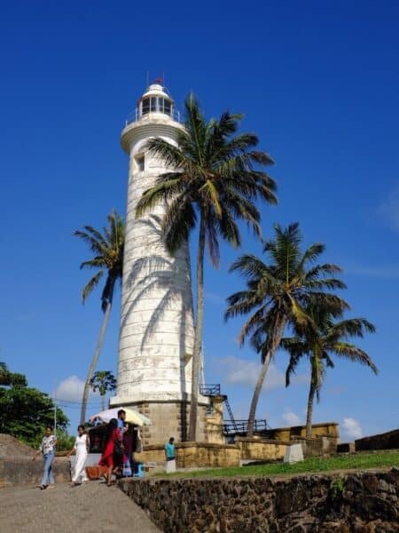 White Galle Fort lighthouse with palm trees and blue sky on Sri Lanka’s south coast.