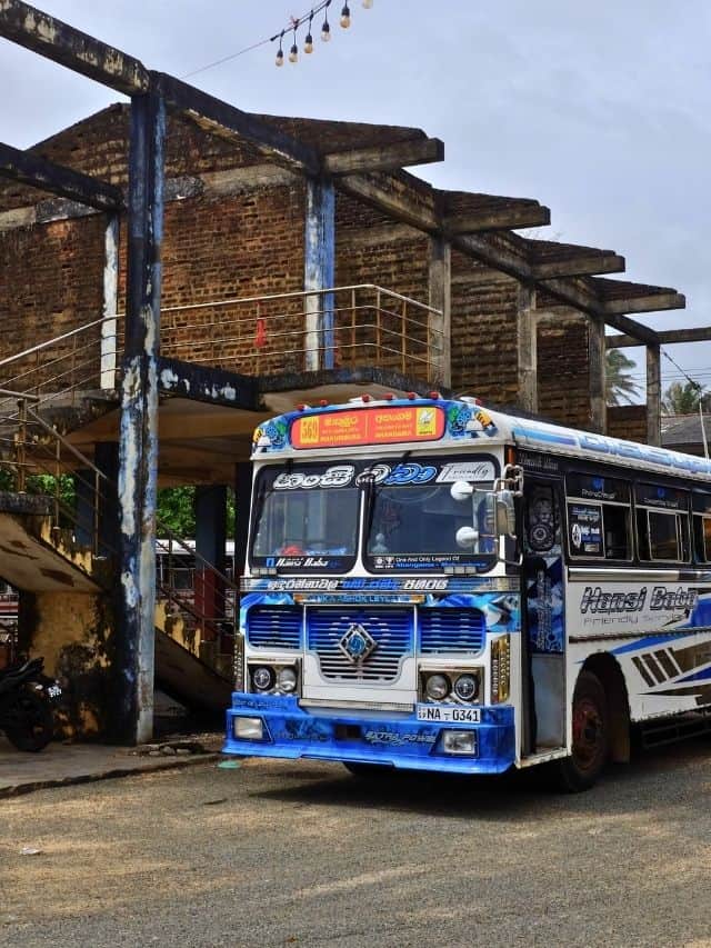 Colourful local bus parked by an old building in Sri Lanka.