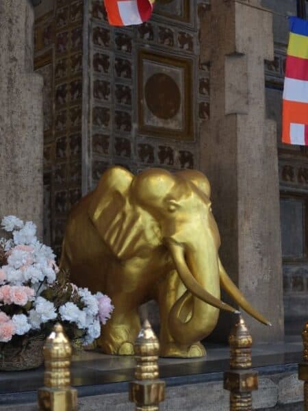 Golden elephant statue and Buddhist flags at the Temple of the Tooth in Kandy.