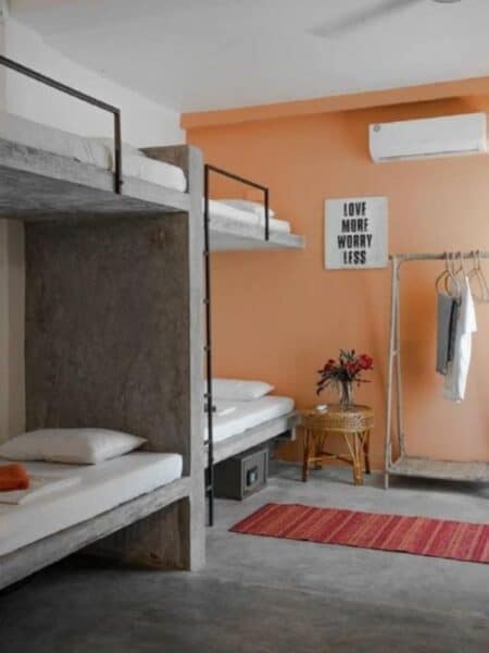 Dorm room with bunk beds, air con and colourful decor at 7BD Surf House in Sri Lanka.