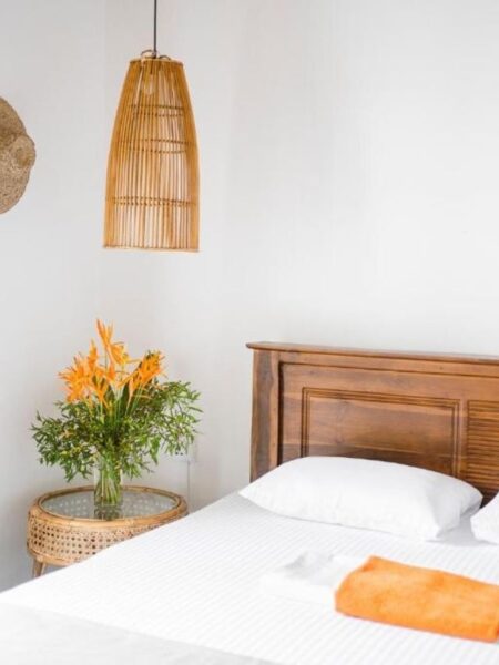 Double room with white bedding, rattan lighting and flowers at 7BD Surf House.