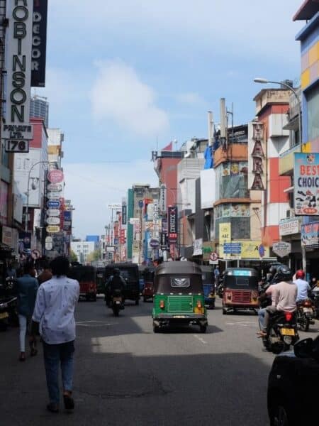 Busy Colombo street with tuk-tuks, shops and traffic during a city tour