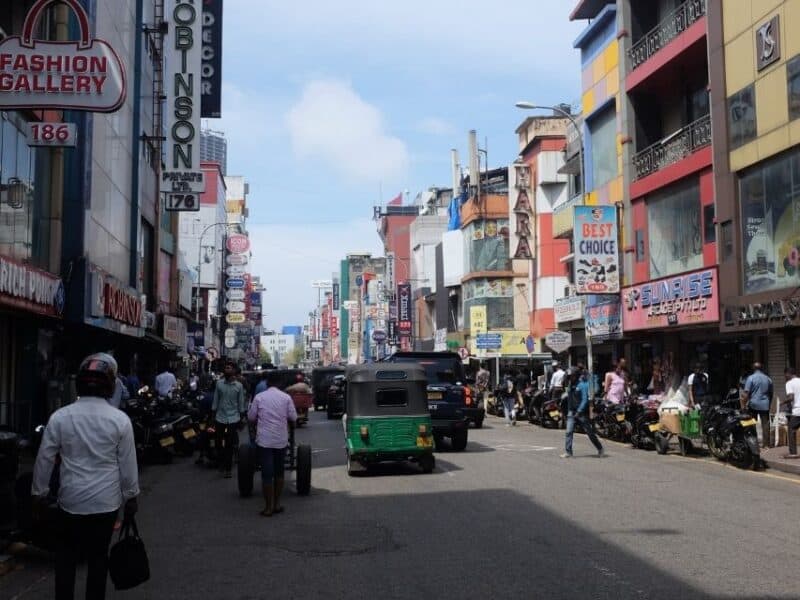 A busy Pettah Street in Central Colombo with traffic and people.