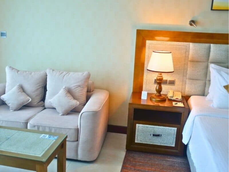 Comfortable hotel room with sofa, bedside lamp and king bed in Colombo.