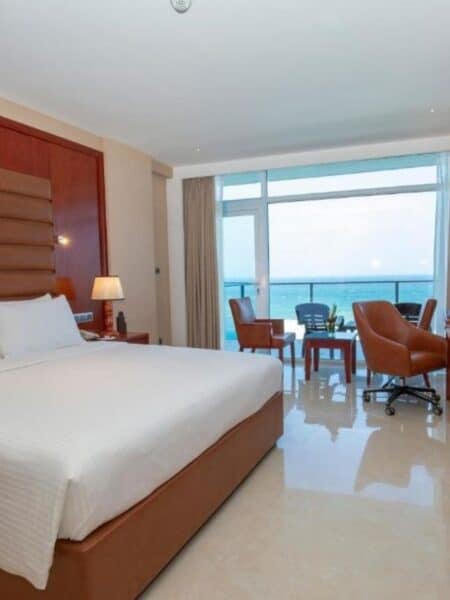 Spacious sea view room at a Colombo hotel with a king bed, balcony and ocean-facing windows.