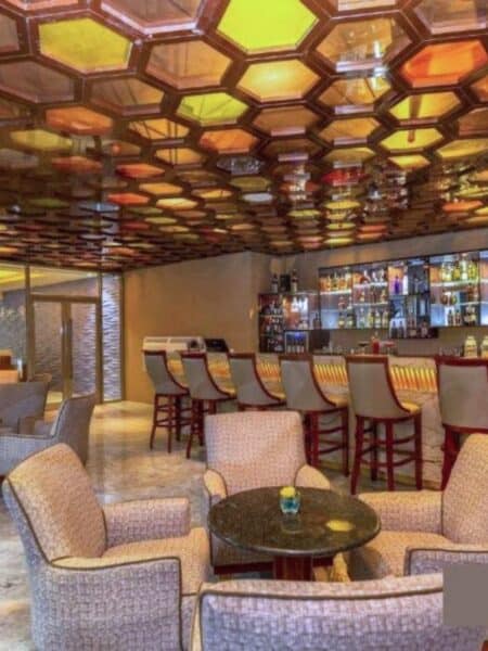 Stylish hotel bar with patterned ceiling, lounge seating and bar stools.