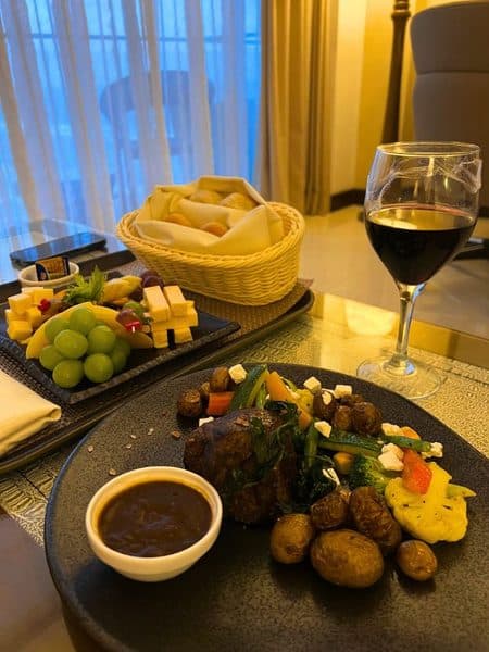 Dinner dishes on a table with a glass of wine in a hotel room