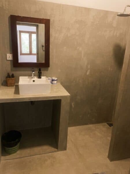 Concrete-style private bathroom with sink and shower at Mellow Hostel.